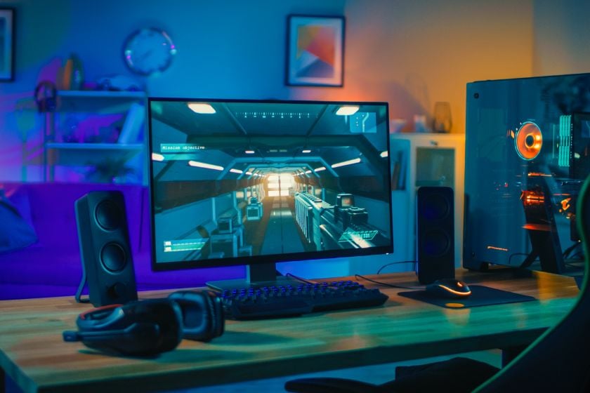 Gaming-Setup mit Monitor, Gaming-PC, Tastatur, Maus und Headset in bunter RGB-Beleuchtung.