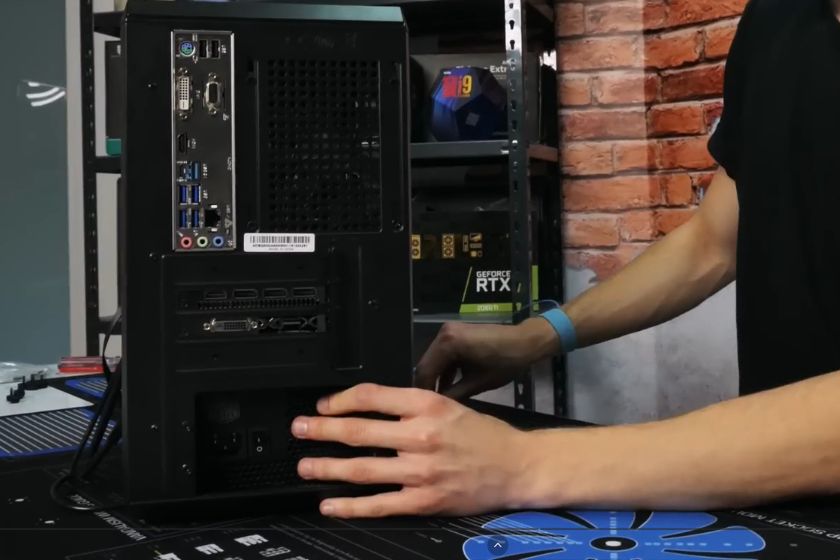 Eine Person setzt gerade das Netzteil in einen PC ein