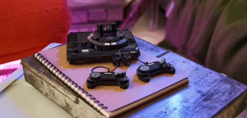 Die LEGO SEGA Mega Drive steht aufgebaut auf einem Tisch. Neben der Konsole liegen zwei Controller, während die Szene mit farbiger Beleuchtung im Retro-Gaming-Stil in Szene gesetzt wird.