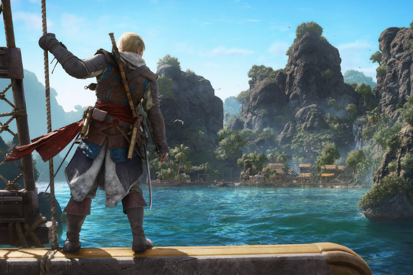 Edward Kenway steht an Bord eines Schiffes und blickt auf eine tropische Insel in der Karibik. Im Hintergrund sind türkisfarbenes Wasser, Palmen und steile Felsformationen zu sehen.