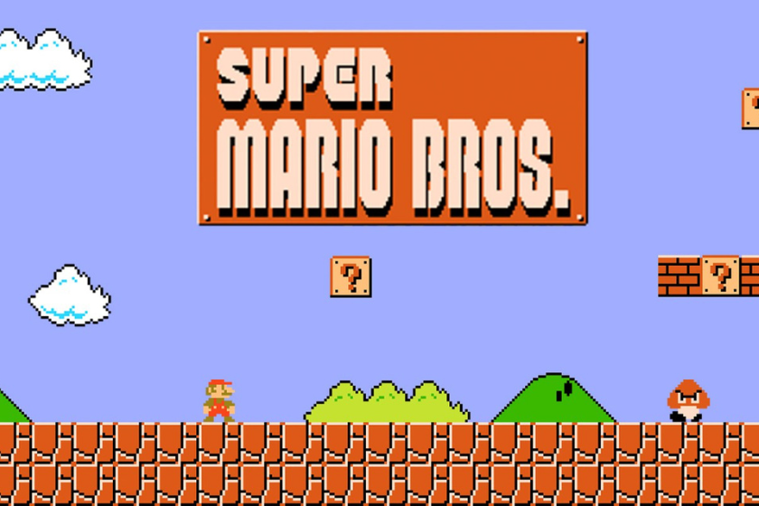 Screenshot des NES-Klassikers Super Mario Bros. mit dem Titelbildschirm des Spiels. Zu sehen sind die typische Pixelgrafik, Mario auf einer Plattform, ein Goomba-Gegner, grüne Hügel, Wolken sowie die ikonischen Fragezeichen-Blöcke vor blauem Hintergrund.