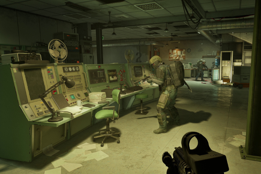 Screenshot aus PUBG: Black Budget: Ein bewaffneter Soldat durchsucht einen verlassenen Kontrollraum voller Computer und Technik. Im Hintergrund sind weitere Einsatzkräfte zu sehen. Die düstere Atmosphäre und die heruntergekommene Forschungseinrichtung vermitteln den Eindruck eines gefährlichen Extraction-Shooter-Einsatzes.
