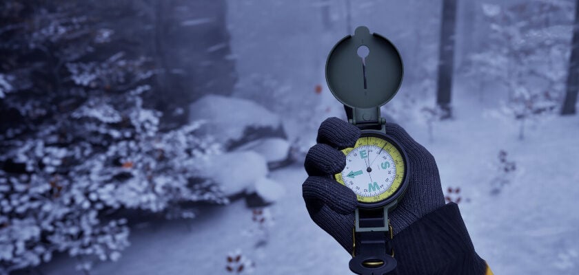 Das Bild zeigt eine verschneite Waldlandschaft aus der Ego-Perspektive, in der eine Person mit Handschuh und gelber Jacke einen geöffneten Kompass in der Hand hält. Im Hintergrund sind schneebedeckte Bäume, Felsen und ein schmaler Pfad zu erkennen, wodurch die Szene den Eindruck einer winterlichen Erkundung oder Survival-Situation vermittelt.