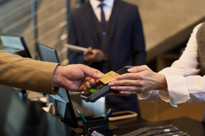 Eine Person bezahlt mit einer Kreditkarte an der Rezeption eines Hotels.