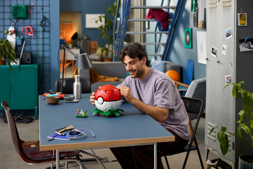Person baut den LEGO Pokémon Pokéball mit Trainermomenten und den enthaltenen Minifiguren.