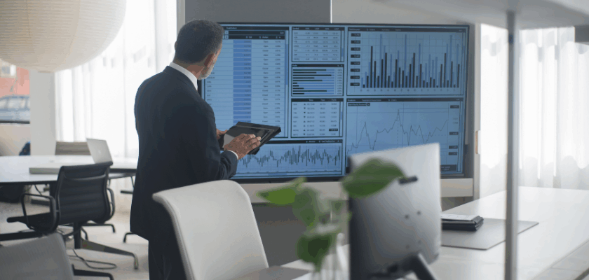Person analysiert Finanzdaten und Diagramme auf einem großen Bildschirm in einem modernen Büro.
