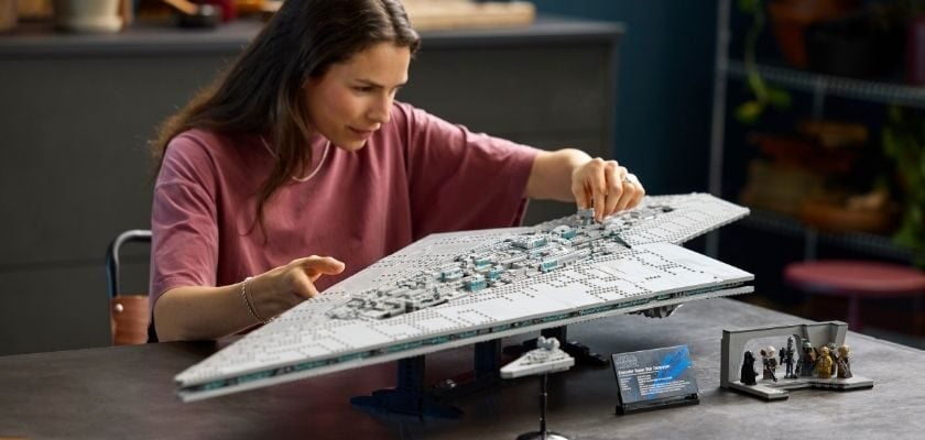 Frau baut den LEGO Star Wars UCS Executor Supersternzerstörer (75457) auf einem Tisch zusammen. Daneben stehen mehrere Star-Wars-Minifiguren sowie ein kleines Raumschiff-Modell.