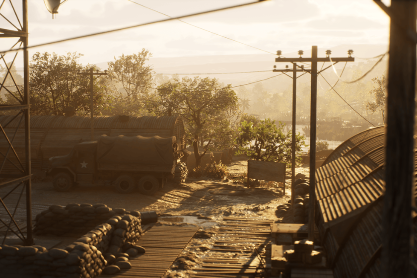 Spielszene aus Hell Let Loose: Vietnam mit einem Militärstützpunkt, Sandsäcken und einem Armeelastwagen in der vietnamesischen Landschaft.