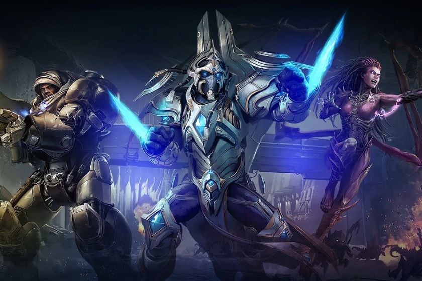 Drei Charaktere aus StarCraft stehen kampfbereit nebeneinander, darunter ein schwer bewaffneter Soldat, ein Protoss-Krieger und eine Zerg-Kämpferin