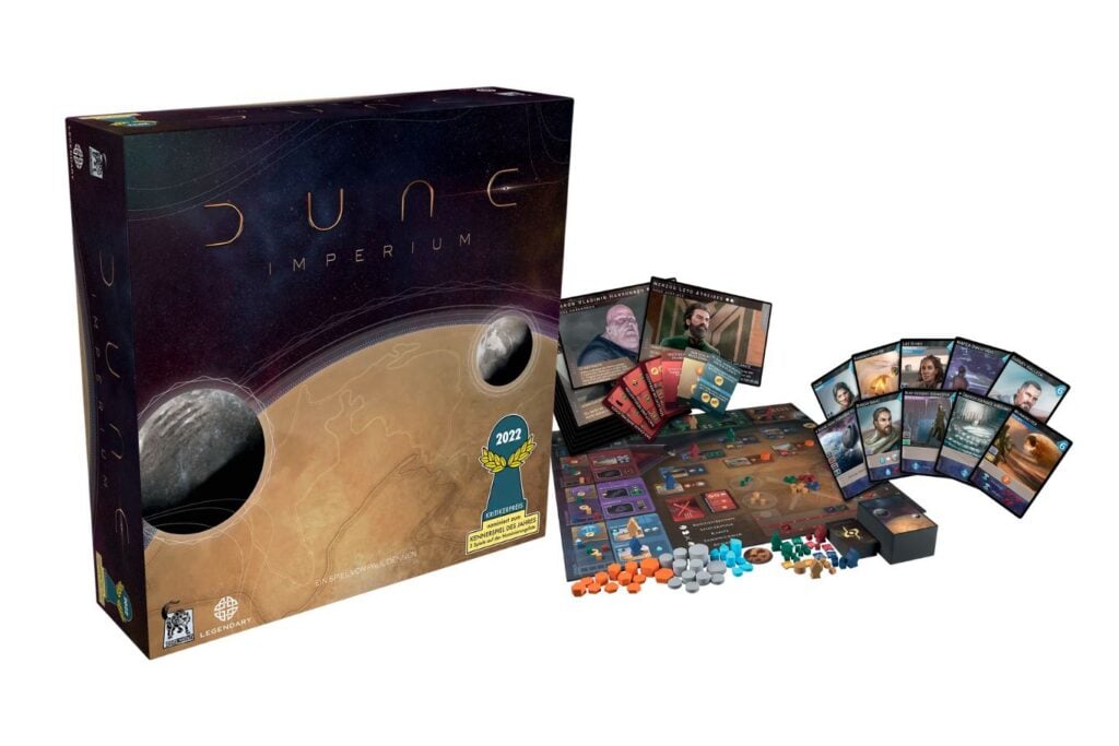 Abbildung des Strategiespiels "Dune: Imperium" in der Spielverpackung und den ausgepackten Spielkarten und Figuren rechts daneben.