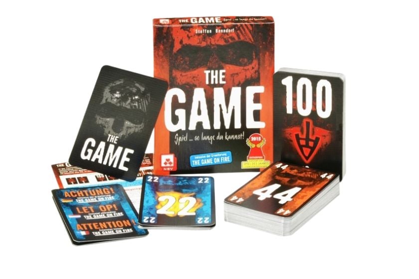 Abbildung des Kartenspiels "The Game" mit Verpackung und ausgepackten Spielkarten davor.