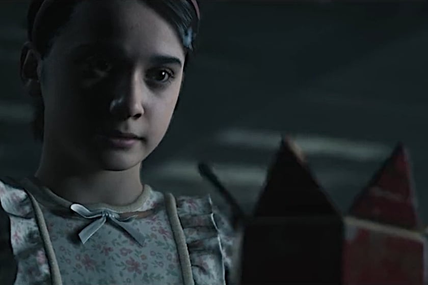 Junges Mädchen in einem geblümten Kleid blickt in einer düsteren Szene aus The Conjuring: Stillschweigen auf eine geheimnisvolle Box.