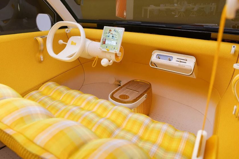 Gelber Innenraum des Citroën 2CV Concept mit weißem Lenkrad, zentralem Touchscreen, karierten Sitzen und einem Korb im Fußraum.