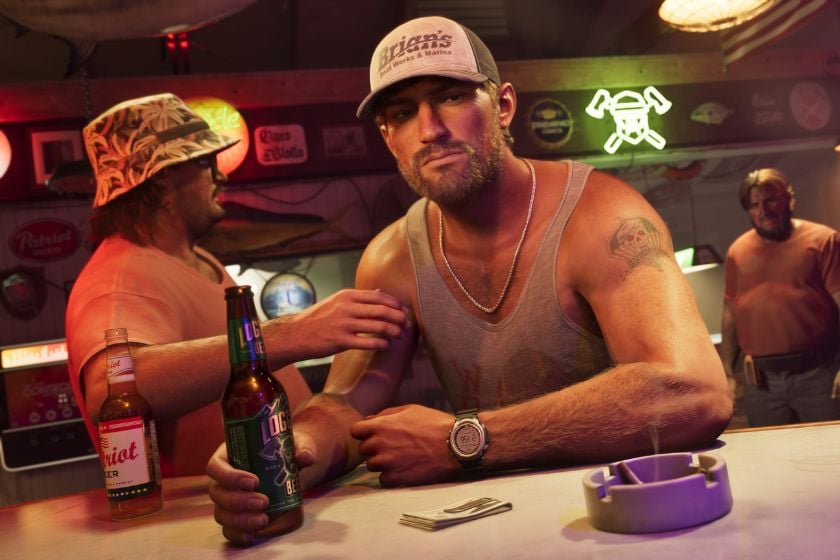 Jason aus GTA 6 sitzt mit einer Bierflasche an einer Bar. Neben ihm stehen zwei weitere Männer in einer schummrig beleuchteten Kneipe.
