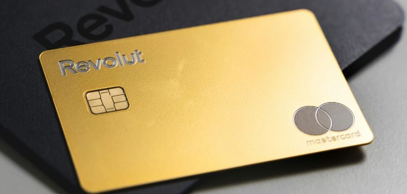 Goldene Revolut-Mastercard mit Chip auf einer schwarzen Kartenverpackung mit Revolut-Logo.