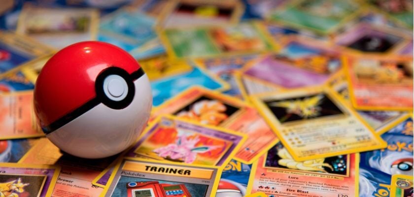 Ein rot-weißer Pokéball liegt auf zahlreichen bunt verteilten Pokémon-Sammelkarten.