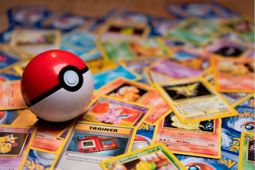 Ein rot-weißer Pokéball liegt auf zahlreichen bunt verteilten Pokémon-Sammelkarten.